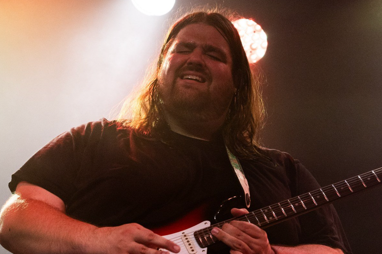 Blues rock guitarist and singer Stefan Hauk performing live with an electric guitar under stage lights.
